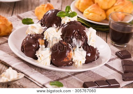 Chocolate Profiteroles With Whipped Cream On White Dish.