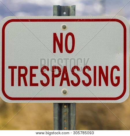 Square Close Up Of White Sign Board With The Words No Trespasing Painted In Red Color