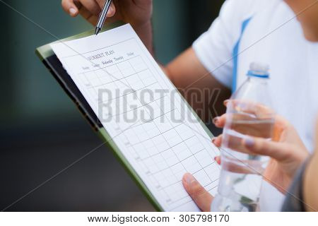 Fitness Plan. Sports Trainer Amounts To Workout Plan Close-up