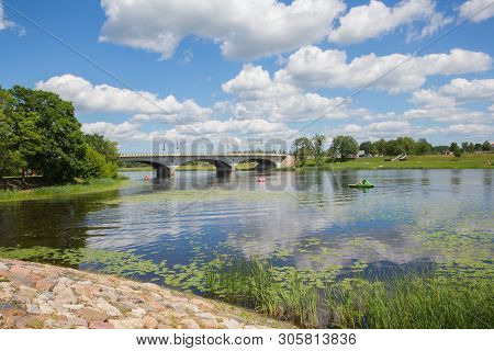 City Jelgava, Latvian Republic. River Lielupe,  People Are Driving Catamaran. Bridge And Water. Jun