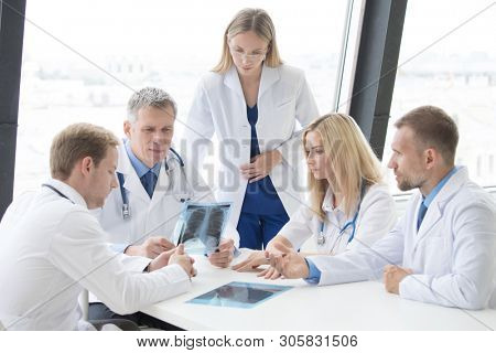 Group of doctors look and discuss x-ray in a clinic or hospital
