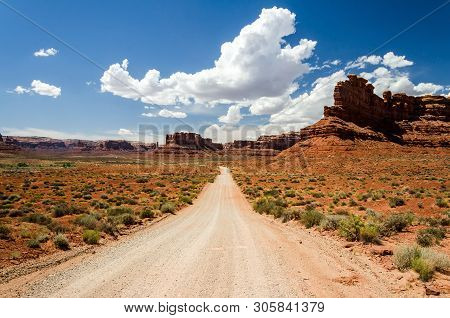 Dirt Road In The Desert With Red Rocks In The Background