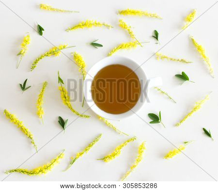 Herbal Tea In A Porcelain Cup.melilotus Officinalis, Known As Yellow Sweet Clover On White Table. Us