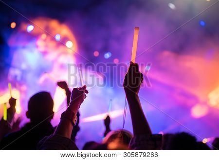 Young Teenager Girl Fan Raised Up Two Hands With Colored Glowing Sticks Supporting Favorite Popular 