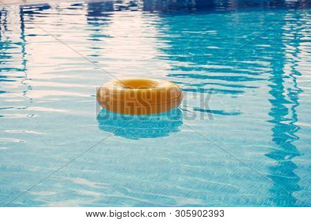 floating ring on blue water swimpool with waves reflecting in the summer sun