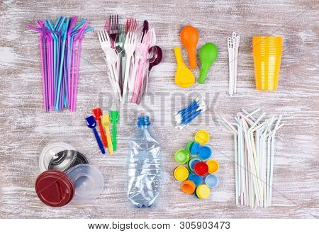 Disposable single use plastic objects such as bottles, cups, forks, spoons and drinking straws that cause pollution of the environment, especially oceans. Top view.