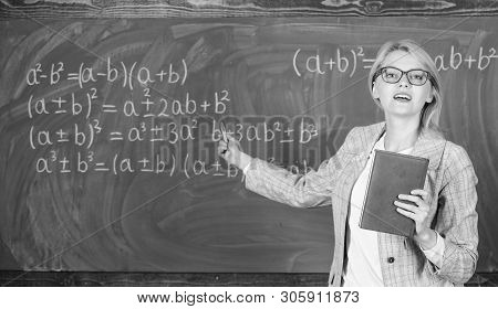 Teacher Smart Woman With Book Explain Topic Near Chalkboard. School Teacher Explain Things Well And 