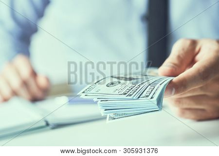 Man Giving Money Us Dollar Banknotes And Holding Cash In Hands. Money Credit Concept. Toned Picture.