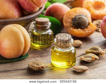 Apricot kernel oil and apricot kernels on wooden background.