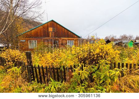 Esso, Kamchatka Peninsula, Russia- 02 October 2014: Wooden Small House And Bush With Fence In Front 