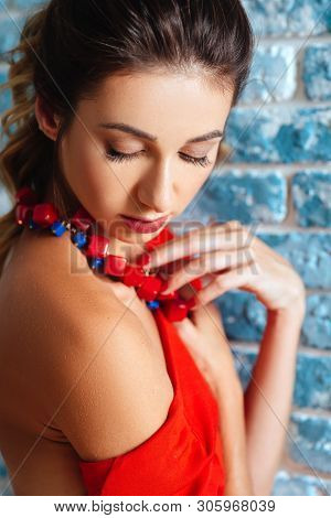 Beautiful Young Woman In Red Dress Is Laughing And Gesturing. Tudio Shot On Gblue Background.
