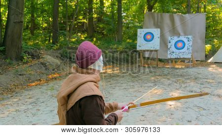 Medieval Male Archer Shooting Targets With Wooden Bow At Historical Festival. Archery And Medieval C