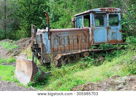 Rusty Abandoned Tractor Outcast In Green Forest