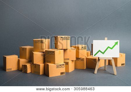Lots Of Cardboard Boxes And A Stand With A Green Up Arrow. Rate Growth Of Production Of Goods And Pr