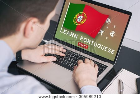 Man Working On Laptop With Learn Portuguese On A Screen. Education Learning Portuguese Language Scho