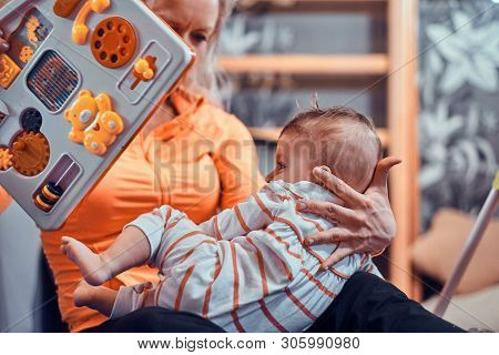 Joyful Happy Mom Is Playing With Her Newborn Baby While Waiting For A Doctor At Pedeatrician Cabinet