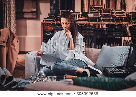 Beautiful Young Designer Is Sitting On The Sofa At Her Curtians Atelier While Watching Drawings Abou