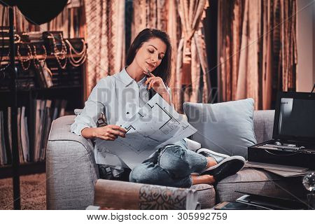 Beautiful Young Designer Is Sitting On The Sofa At Her Curtians Atelier While Watching Drawings Abou