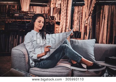 Beautiful Young Designer Is Sitting On The Sofa At Her Curtians Atelier While Watching Drawings Abou