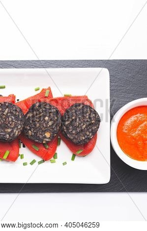 Slices Of Spanish Black Pudding On Piquillo Peppers In White Plate On White Background. Spanish Tapa