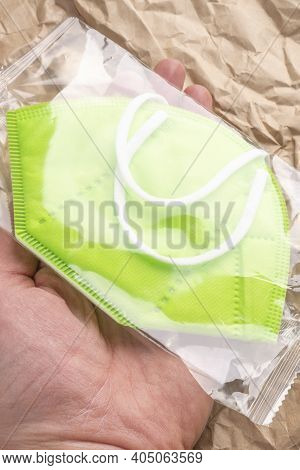 New Green Medical Protective Mask Kn95 In A Plastic Transparent Package In A Hand Close-up. Crumpled