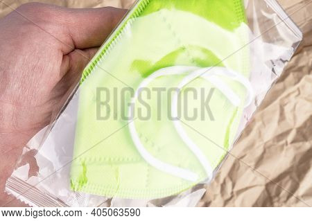 Pack With A Respiratory Medical Mask Kn 95 In Hand On A Background Of Wrinkled Kraft Paper. Concept 