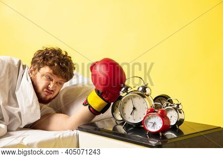 Dumb. Man Wakes Up At His Bed On Yellow Background And Hes Mad At Clocks Ringing, Switches It Off Wi