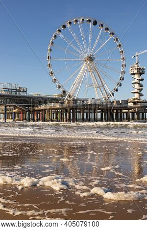Ferris Wheel On De Pier In The Hague With Blue Sky And Calm Water At The Beach Of Scheveningen, Neth