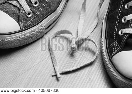 Heart-shaped Bootlaces Between Men's And Women's Sneakers. Love Concept. Black And White Image.