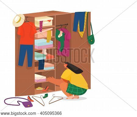 Girl Squatting Rummages In Wooden Cabinet. Clothes On Hangers In The Cupboard. Choose Or Fold Clothe