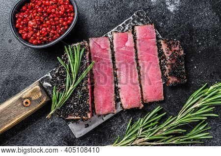 Rare Ahi Tuna Steak Slices On A Meat Cleaver. Black Background. Top View.