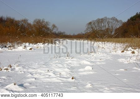 Winter Sunny Day. The Small Small River Was Held Down By Ice And From Above Covered White Fluffy Sno