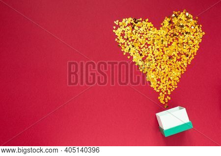 Gold Sparkles In The Shape Of A Heart With Gift Box On Red Background Happy Valentines Day Concept F