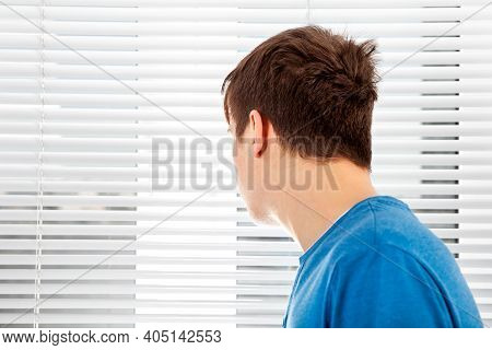 Rear View Of A Young Man Next To Jalousie In A Room
