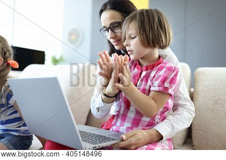 Woman Holds Laptop On Lap Of Little Girl Sitting. Remote Work From Home With Children Concept