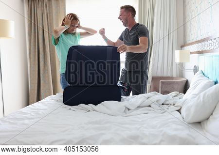 Man And Woman Are Fighting In Bedroom Near Suitcase.