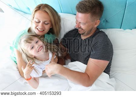Parents With Child Indulge And Cuddle In Bed. What Is Use Of Parental Hugs For Child Concept