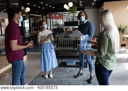 Diverse group of business people working in creative office. group of people wearing face masks and discussing work. social distancing protection hygiene in workplace during covid 19 pandemic.
