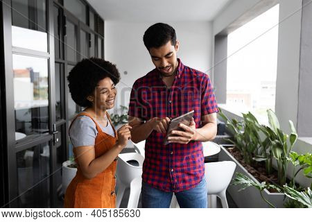 Two mixed race business people working in creative office. two people standing and discussing work. business people and work colleagues at a busy creative office.