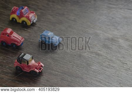 Children's Imaginary Concept Games. Little Toy Cars Racing Headlong Across A Brown Wooden Surface. V