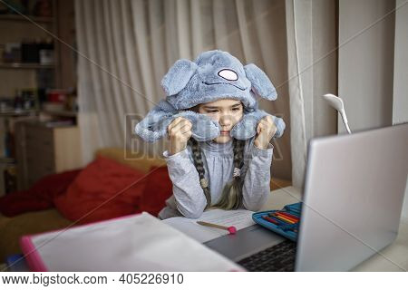 Distant Education, Online Class Meeting. Girl Wearing Funny Hat For Amusement During Online Lesson