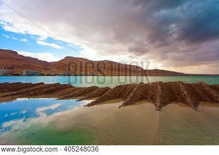 Legendary Dead Sea. The smooth surface of the very salty sea water reflects the sky and clouds. Low winter clouds are reflected in the green sea water. Israel