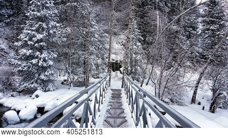 First-person View Of A Metal Bridge In The Forest. I Walk Across A Bridge In A Snowy Gorge, Among Wh