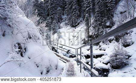 First-person View Of A Metal Bridge In The Forest. I Walk Across A Bridge In A Snowy Gorge, Among Wh