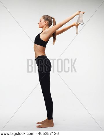 Motivation, fitness and people concept: Sporty young woman doing a exersize with resistance band. Photo of young woman in fashionable sportswear on white background.