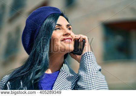 Young beautiful woman wearing french style talking on the smartphne at the city.