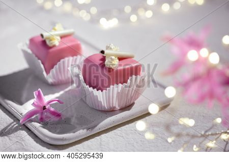 Valentine Petit Fours With Marzipan Icing. Fragrant Pink Hyacinth Flower. Garland Of Lights On White