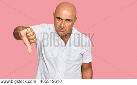 Mature middle east man with mustache wearing casual white shirt looking unhappy and angry showing rejection and negative with thumbs down gesture. bad expression. 