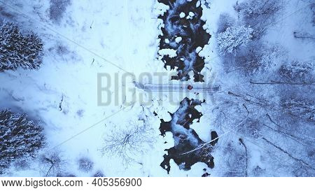 The Guy Is Walking On The Bridge Over The River. The View From The Drone To The Tall Trees, The Rive