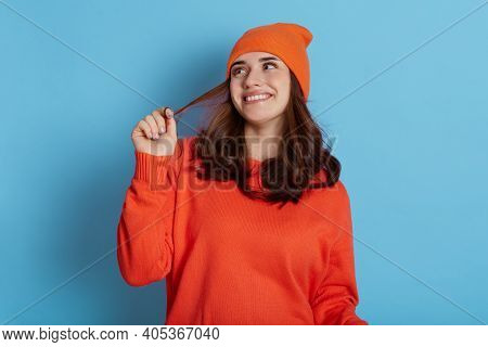 Young Beautiful Lady Dreamily Looks Aside, Smiling Happily Isolated Over Blue Background, Pulling He